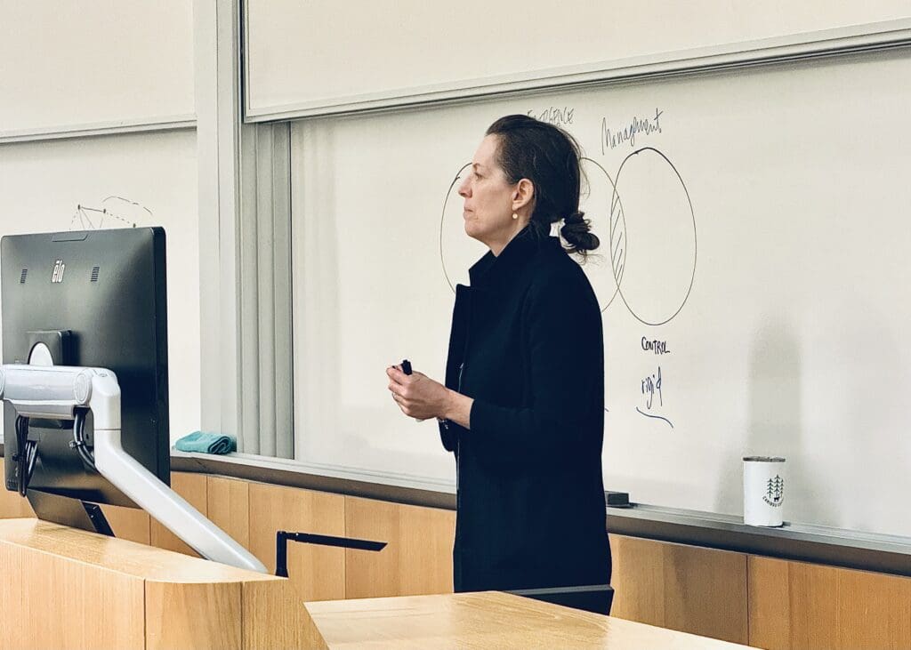 At BarCamp Philly 2023, a speaker guides her audience on how an idea is generated. Behind her is an abstract graph drawn on a whiteboard.